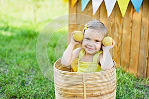 Little child girl with lemons at lemonade stand in park. Portrait of funny baby in basket with fruits