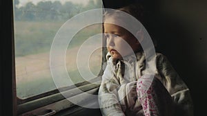 Little child girl looking out of a asian train window