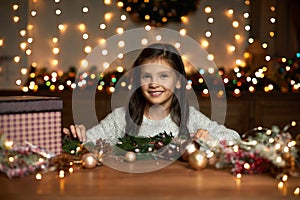 Little child girl makes a handmade Christmas wreath