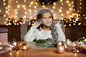 Little child girl makes a handmade Christmas wreath