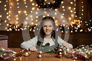 Little child girl makes a handmade Christmas wreath