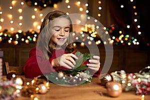 Little child girl makes a handmade Christmas wreath