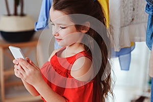 little child girl making selfie while trying on new clothes in her wardrobe or store fitting room