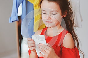 little child girl making selfie while trying on new clothes in her wardrobe or store fitting room