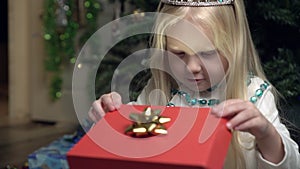 Little child girl opens a box with a Christmas surprise gift.