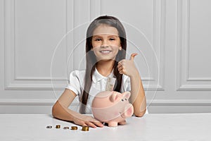 Little child girl with piggy bank at home