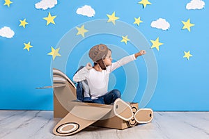 Little child girl in a pilot`s costume is playing and dreaming of flying over the clouds.