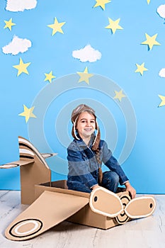 Little child girl in a pilot`s costume is playing and dreaming of flying over the clouds.