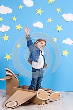 Little child girl in a pilot`s costume is playing and dreaming of flying over the clouds.