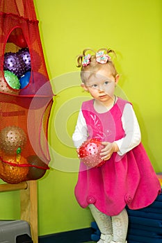 Little child girl playing with ball in kindergarten in Montessori Class.