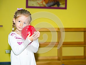 Little child girl playing with ball in kindergarten in Montessori preschool Class. Adorable kid in nursery room.