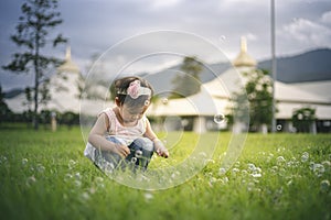 Little child girl playing with bubbles on green grass outdoors in the park