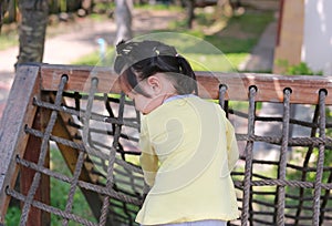 Little child girl playing on climbing net