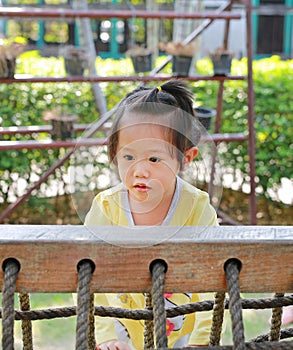 Little child girl playing on climbing net