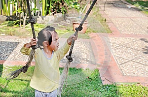 Little child girl playing on climbing rope