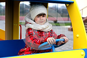 Little child girl playing on playground outdoors in car