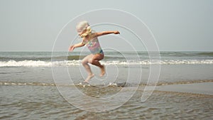 Little child girl playing in waves on the seashore. Child swims in the sea in shallow water