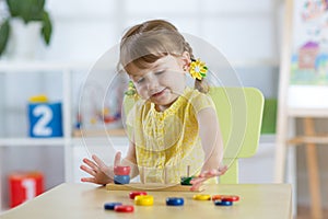 Little child girl plays in kindergarten in Montessori preschool class.