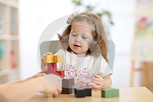 Little child girl plays in kindergarten in Montessori preschool class.