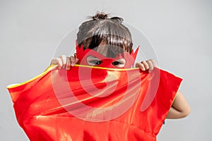 Little child girl plays superhero. Child on the white background. Girl power concept