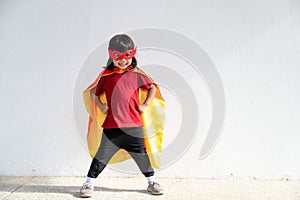 Little child girl plays superhero. Child on the white background. Girl power concept