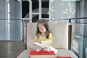 Little child girl reading book in library, Education concept