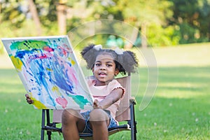 Little child girl shows her painting work. Cute kid show painting work in the garden