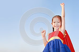 Little child girl Superhero in a gesture to fly on clear blue sky background. Kid super hero concept