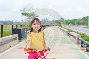 Little child girl to ride bicycle in outdoor sports ground on sunny summer day. Active leisure and outdoor sport for children