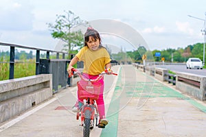 Little child girl to ride bicycle in outdoor sports ground on sunny summer day. Active leisure and outdoor sport for children