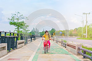 Little child girl to ride bicycle in outdoor sports ground on sunny summer day. Active leisure and outdoor sport for children