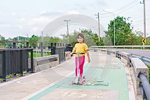 Little child girl to ride scooter in outdoor sports ground on sunny summer day. Active leisure and outdoor sport for children