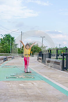 Little child girl to ride scooter in outdoor sports ground on sunny summer day. Active leisure and outdoor sport for children