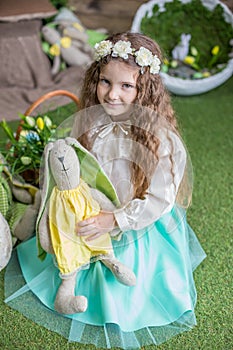 Little child girl with toy bunny among Easter studio decoration