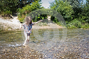 Little child girl wading a stream on a bright sunny day. Parco del Ticino, Italy