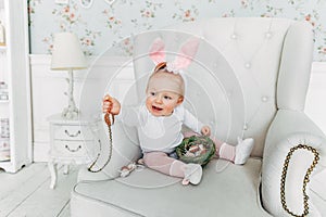 Little child girl wearing bunny ears on Easter day and playing with painted eggs