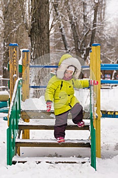 Little child goes down the stairs in winter playground