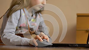 Little child hand is holding a computer mouse on laptop screen background. Remote online education during quarantine and