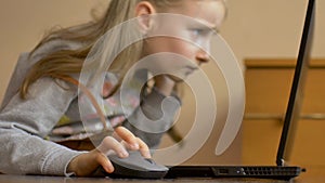 Little child hand is holding a computer mouse on laptop screen background. Remote online education during quarantine and