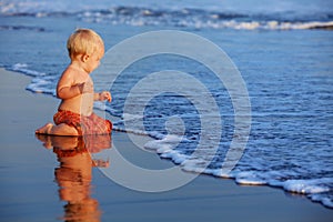 Little child has a fun on black sand sunset sea beach