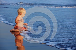 Little child has a fun on black sand sunset sea beach