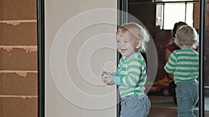 Little child have fun, play with ball near mirror