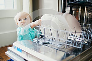 Little child helping to unload dishwasher