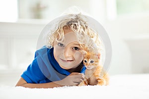 Little child holding baby cat. Kids and pets
