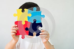 A little child holding a puzzle symbol of Public awareness for autism spectrum disorder.