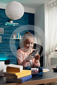 Little child holding smartphone reading online story using virtual book