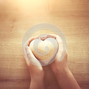 Little child holding a wooden heart. father`s and mother`s day, love, hope and religion concept