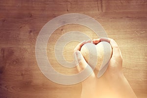 Little child holding a wooden heart. father`s and mother`s day, love, hope and religion concept