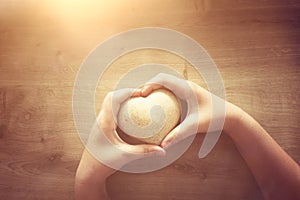 Little child holding a wooden heart. father`s and mother`s day, love, hope and religion concept