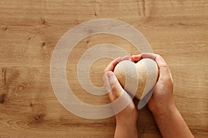 Little child holding a wooden heart. father`s and mother`s day, love, hope and religion concept